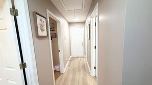 A hallway with a wooden floor, white doors, and framed pictures on the walls.