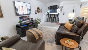 A living room with a sofa, a coffee table, and a TV. There is a dining area with a table and chairs. - 2 Connected Private Suites| 0.4mi OWU |Free Parking|Quiet Street|Patio|W/D (Delaware)