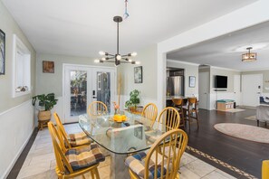 A dining area with a glass table, wooden chairs, and a modern chandelier.