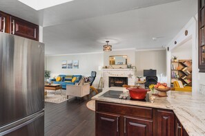 A modern kitchen with a built-in stove, a large refrigerator, and a dining area with a wooden table and chairs.