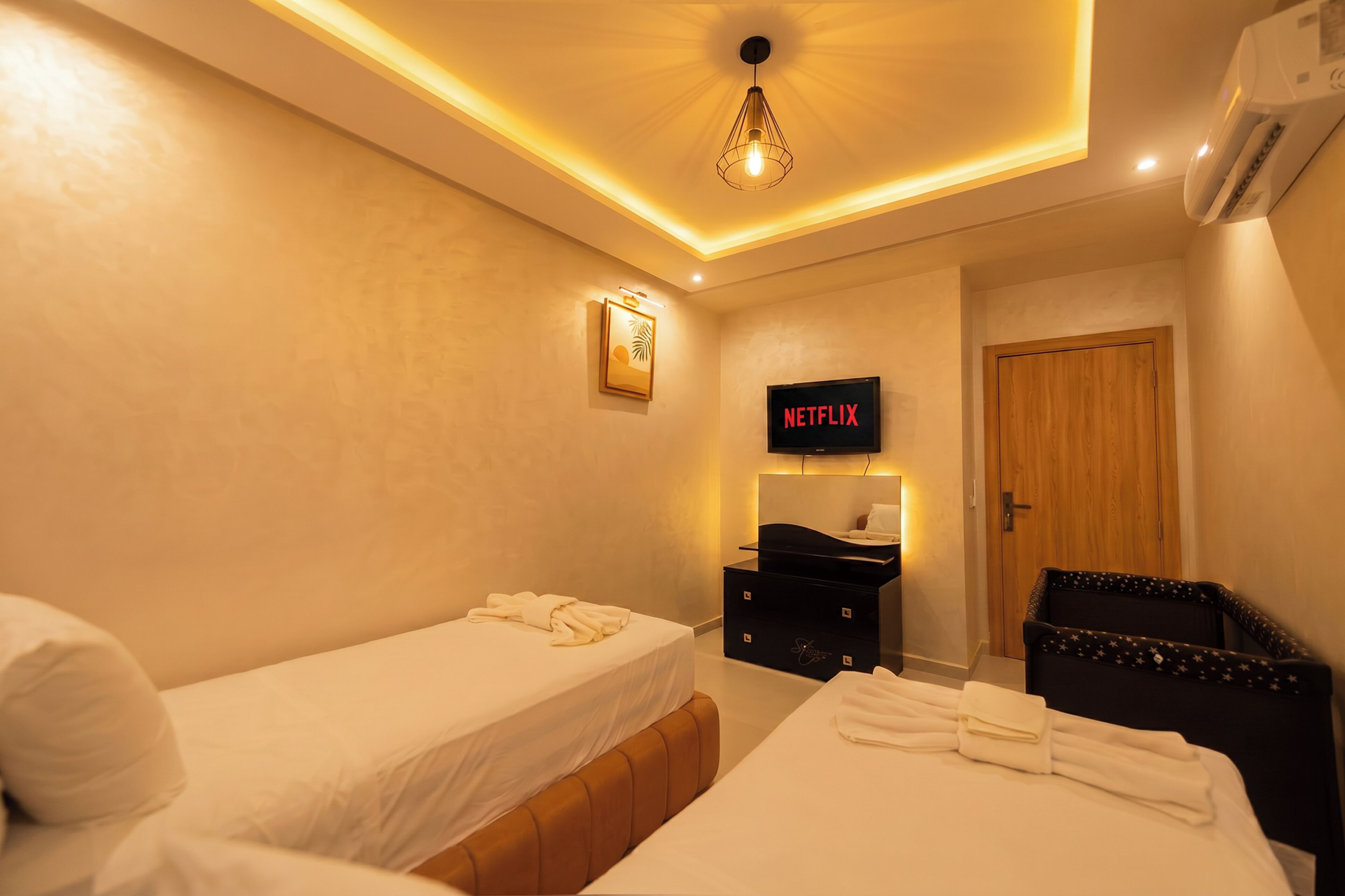 A hotel room with two beds, a TV, a wardrobe, and a door.