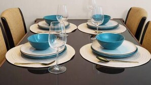 Une table à manger avec des bols bleus, des verres à vin et une suspension noire.