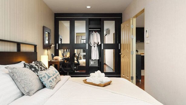 Une chambre d’hôtel comprenant un lit, un bureau, une chaise, une armoire et un miroir.