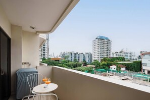 A balcony with a table and chairs, overlooking a cityscape with high-rise buildings. - MonthlyStays/1GbWiFi/FullKitchen/ComfyKingBed/Tub (Watthana)