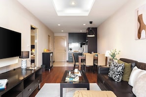 A modern living room with a flat-screen TV, a coffee table, and a sofa. - MonthlyStays/1GbWiFi/FullKitchen/ComfyKingBed/Tub (Watthana)