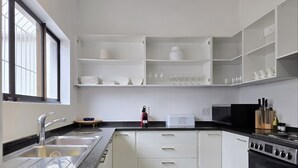 Una cocina moderna con armarios blancos, un lavamanos de acero inoxidable, un microondas, un horno y una panificadora.