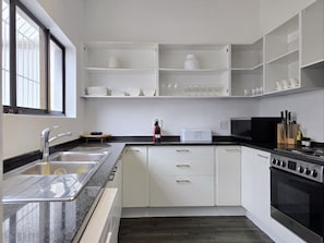 A modern kitchen with white cabinets, a stainless steel sink, a microwave, an oven, and a bread maker. - Spacious & Secure Family Home | 3 Bedrooms | Fresnaye (Cape Town)