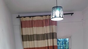 Quarto com cama, cortinas, janela e luminária pendente.