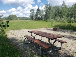 A picnic table with benches in a grassy field.