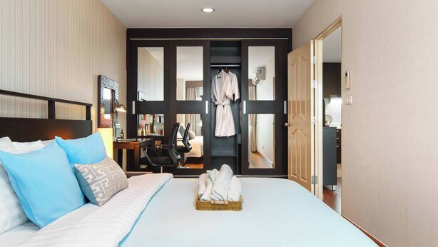 A hotel room with a bed, a desk, a chair, a robe, and a mirror. - 57m²Clean&Quiet/1GbWiFi/Kingbed/Cook/BalconyWasher (Watthana)