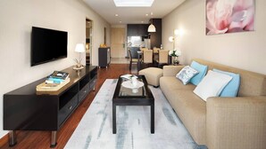 A modern living room with a flat-screen TV, a coffee table, a sofa with cushions, and a dining area with chairs. - 57m²Clean&Quiet/1GbWiFi/Kingbed/Cook/BalconyWasher (Watthana)