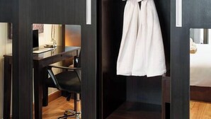 A hotel room with a dark wood wardrobe, a mirror, a robe hanging, a desk with a chair, and a bed. - 57m²Clean&Quiet/1GbWiFi/Kingbed/Cook/BalconyWasher (Watthana)