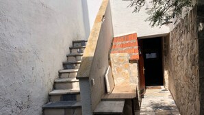 A stone staircase leading to a door, with a tiled floor and a wall with a textured surface. - Mala kuca od soli / Whole house for a dream vacation (Jezera)