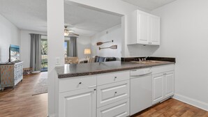 A kitchen with white cabinets, a granite countertop, and a wooden floor. - Trailwoods 3302 (Port Orange)