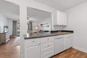 A kitchen with white cabinets, a granite countertop, and a wooden floor. - Trailwoods 3302 (Port Orange)