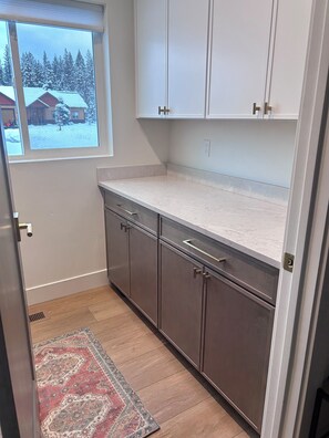 A kitchen with a window, cabinets, and a patterned rug.