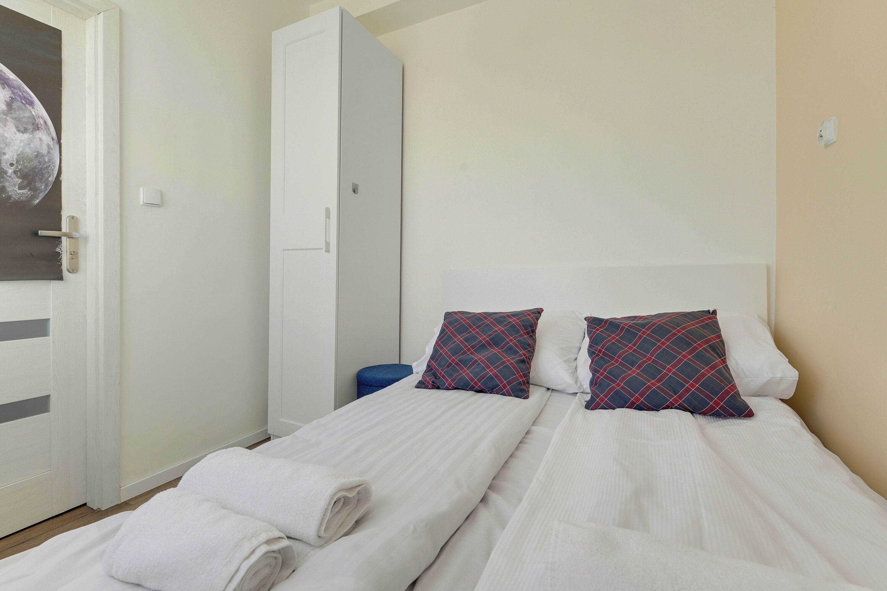 Ein Schlafzimmer mit einem Bett, Kissen, einem blauen Stuhl und einem Kleiderschrank.