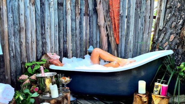 A bathtub filled with water, surrounded by wooden elements and plants. - Fairfield Cottages (Ceres)