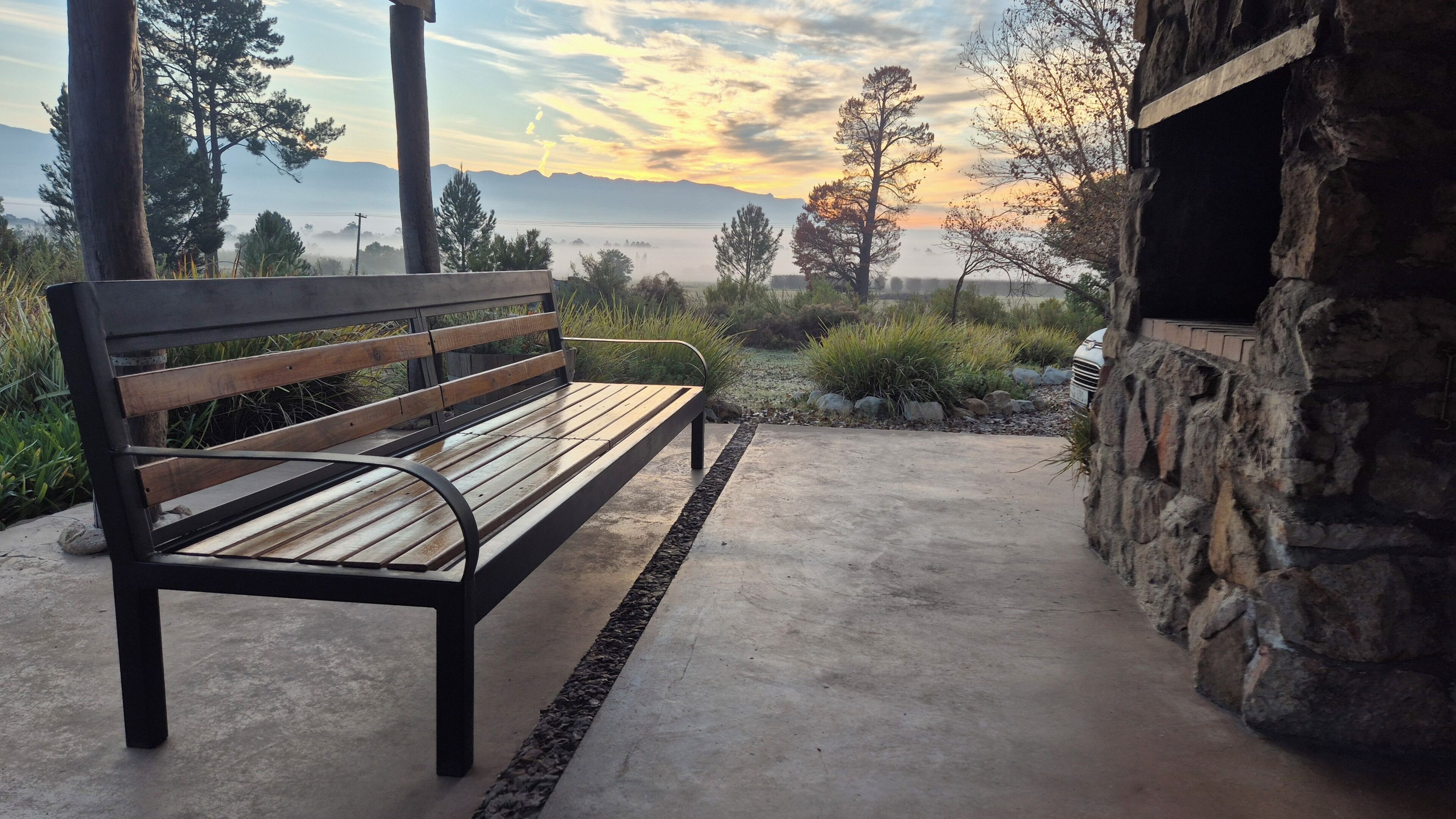 Un banco con vistas a montañas y un atardecer.