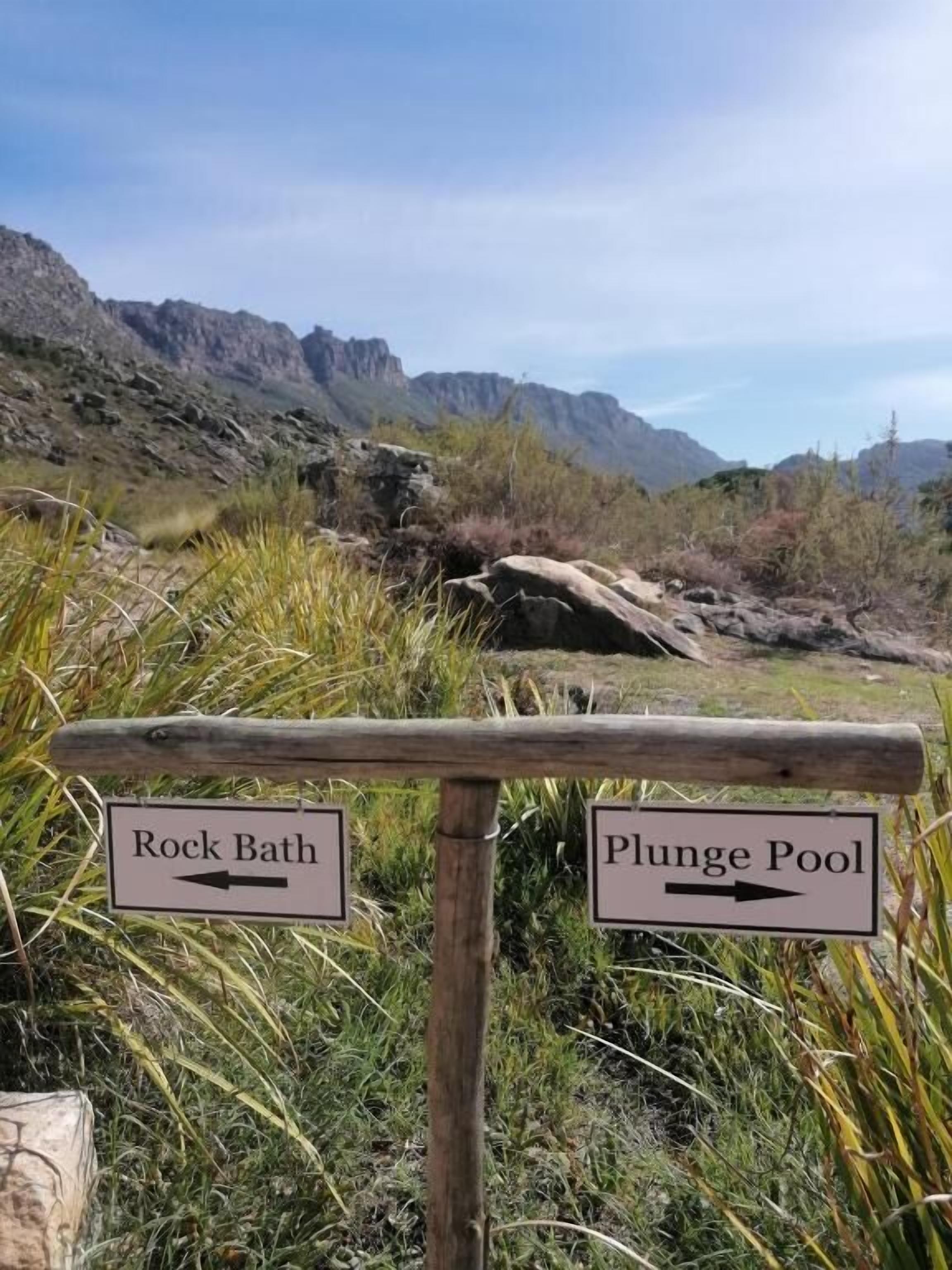 A signpost with directions to 'Rock Bath' and 'Plunge Pool' in a natural setting.