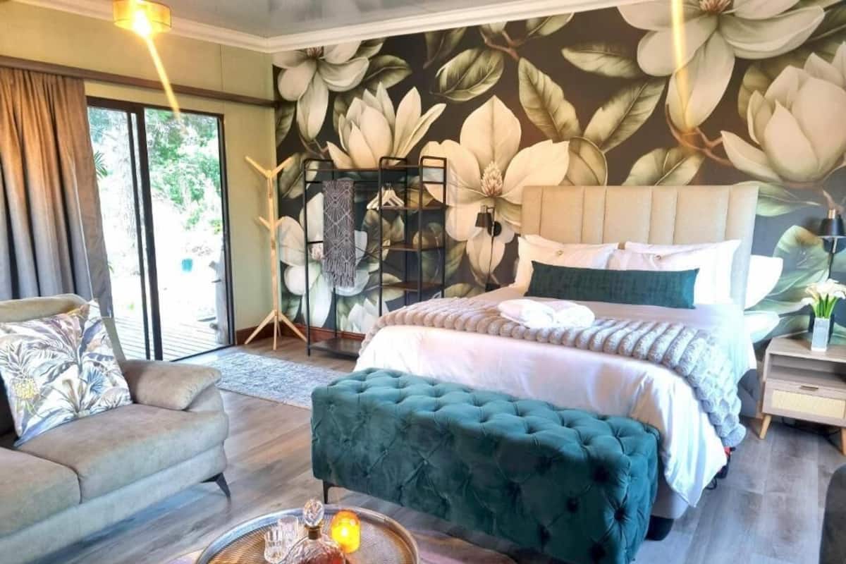 A bedroom with a large bed, a sofa, a coffee table, and a wall with a floral mural.