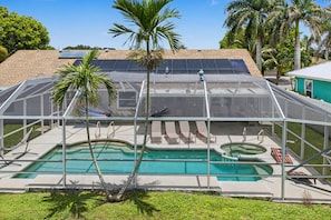 Ein Poolbereich mit Glasveranda, Liegest ühlen und einem Whirlpool.