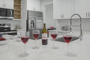 A modern kitchen with stainless steel appliances, a wine bottle, and three wine glasses on the counter. - Splash & Relax Games•PedalBoat•Adventures•Lakeside (Royal Palm Beach)
