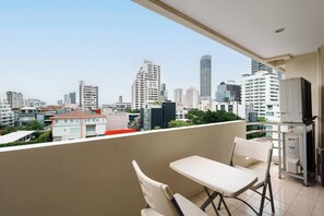 Un balcón con una mesa y sillas, con vistas a un paisaje urbano con edificios modernos.