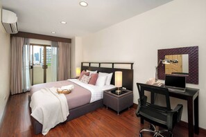 Habitación de hotel con cama, escritorio, silla, lámpara, computadora portátil y ventana con cortinas.
