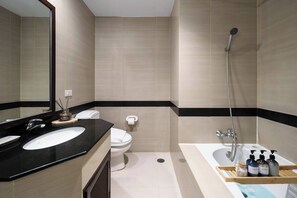 Un baño moderno con lavamanos sobre encimera negra, inodoro blanco, zona de ducha y bañera.