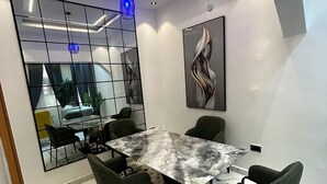 Et moderne mødelokale med et marmorbord, grønne stole, et stort spejl og en moderne lampe.