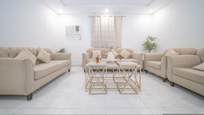 Uma sala de estar moderna com dois sofás, uma mesa de centro e uma luminária no teto.