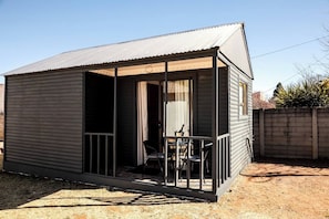 A small, single-story building with a porch and a door leading to an interior space.