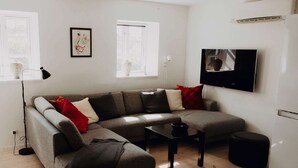 A modern living room with a grey sectional sofa, a small black table, and a white cabinet. - 4 Star Holiday Home in Dronningmolle (Dronningmolle)