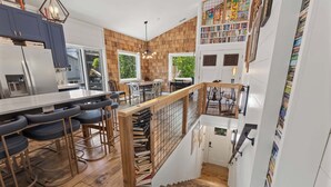 Cozinha moderna com área de bar, piso de madeira e escada que leva a um mezanino.