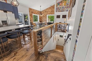 Eine moderne Küche mit Barbereich, Holzboden und einer Treppe, die zu einem Schlafloft führt.
