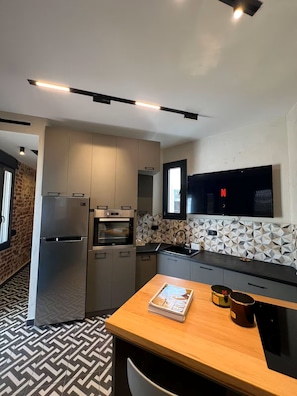 A modern kitchen with built-in appliances, a wooden table, and a patterned floor. - #ALS_ON AIR LUXURY ROOFTOP (Thessaloniki)