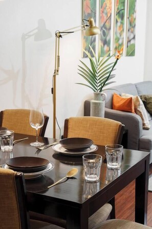 Ein Esstisch mit Tellern, Gläsern, Besteck, einer Lampe und einem Blumentopf.