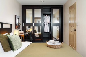 Ein Hotelzimmer mit Bett, Schreibtisch, Stuhl, Bademantel und einem kleinen Korbwäscheschale mit Handtüchern.