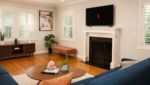 A living room with a fireplace, a television, and a sofa. - Welcome to Brookside Mod Cottage: Spacious and group friendly! (Kansas City)