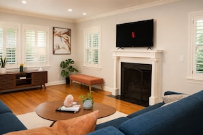A living room with a fireplace, a television, and a sofa. - Welcome to Brookside Mod Cottage: Spacious and group friendly! (Kansas City)