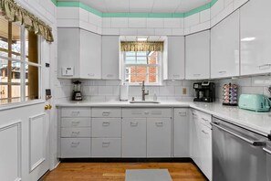 A modern kitchen with white cabinets, a built-in dishwasher, a coffee maker, and a toaster.