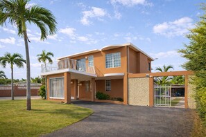 A two-story building with a balcony, large windows, and a gated entrance. - 9BR Home in Dorado PR | Near Beach & Groups (Dorado)