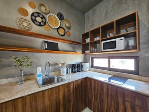 Eine Küche mit Holzschränken, einem Edelstahlspülbecken, einer Mikrowelle und dekorativen Tellern an der Wand.