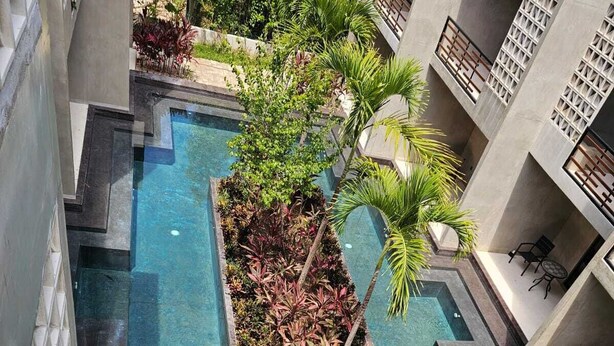Ein Dachpool mit geometrischem Design, umgeben von Pflanzen und einer modernen Gebäudestruktur.