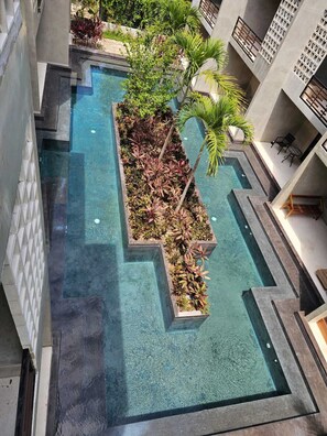 Ein Dachpool mit geometrischem Design, umgeben von Pflanzen und einer modernen Gebäudestruktur.