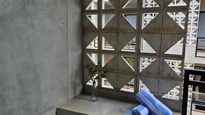 Ein modernes Badezimmer mit einer großen Badewanne, einer Wand mit geometrischem Muster und einem kleinen Fenster mit Pflanze.