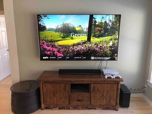 A television mounted on a wall with a wooden entertainment center below. - Trout River Lodge - Discount Jay Peak Lift Tix (Montgomery)