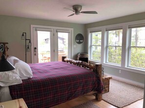 Ein Schlafzimmer mit einem Bett, einem Deckenventilator, einem Fenster und Blick ins Freie.