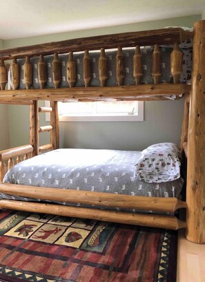 Een stapelbed met houten frame en een beddegoed met patroon.